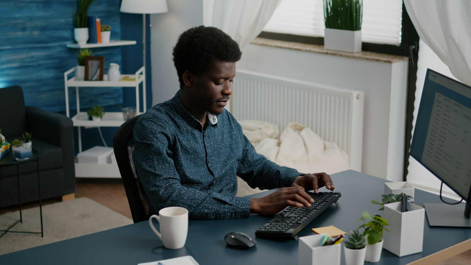 homme afro souriant tape sur son clavier d'ordinateur