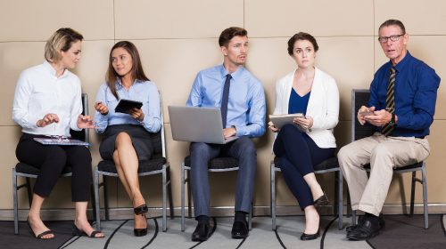 hommes et femmes assis sur des chaises en attendant de passer des entretiens de travail