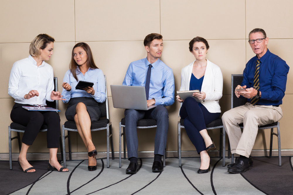 hommes et femmes assis sur des chaises en attendant de passer des entretiens de travail