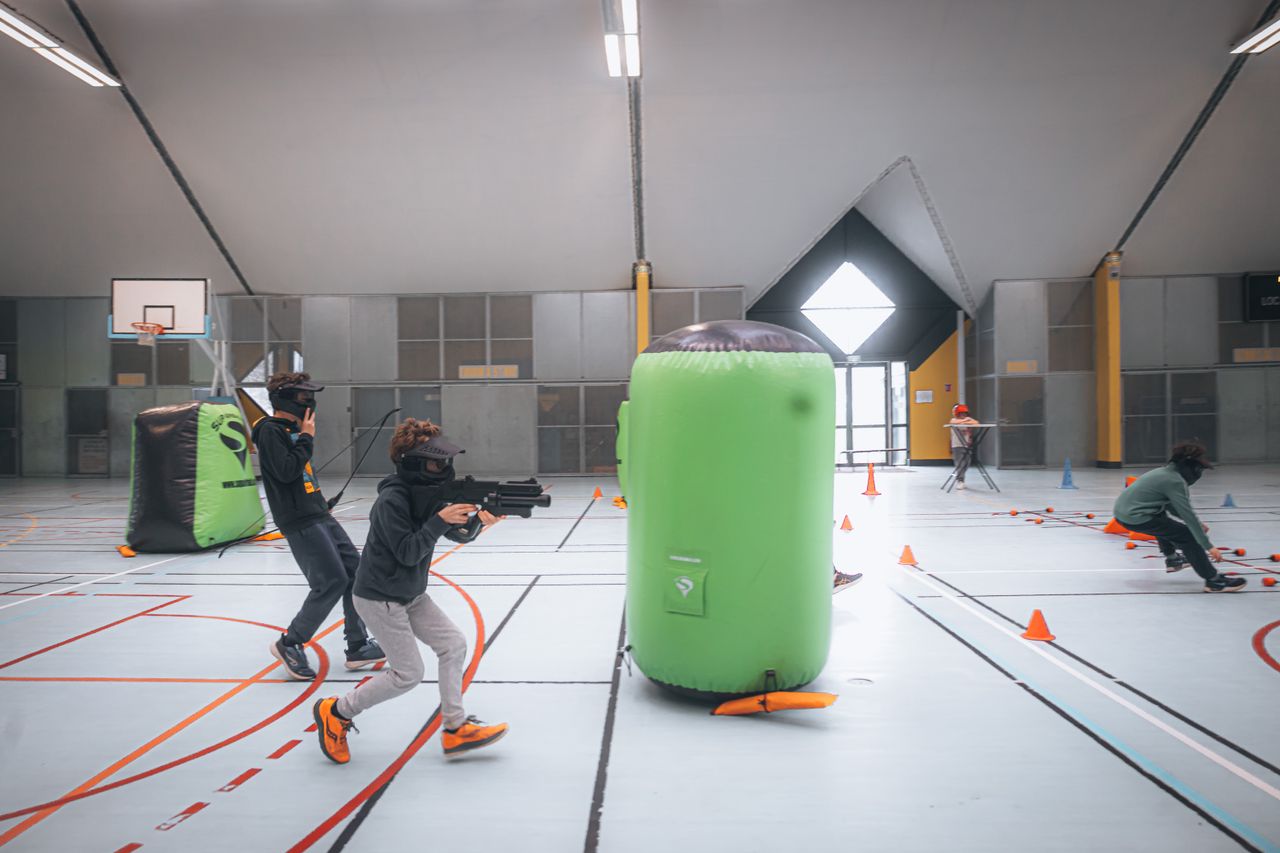 Energetic teenagers playing an indoor laser tag game with vibrant inflatables and obstacles.