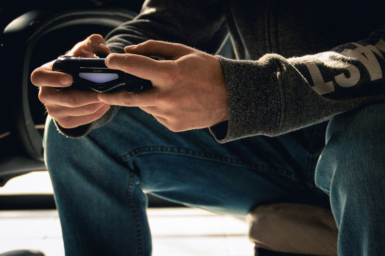 A close-up image of hands holding a game controller, emphasizing a gaming session indoors.